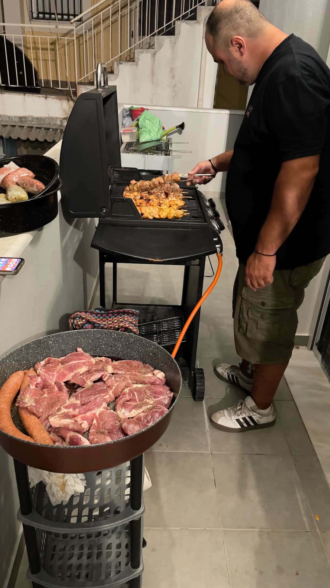 Στημένος σταθμός BBQ με μαριναρισμένο χοιρινό και λουκάνικα έτοιμα για ψήσιμο